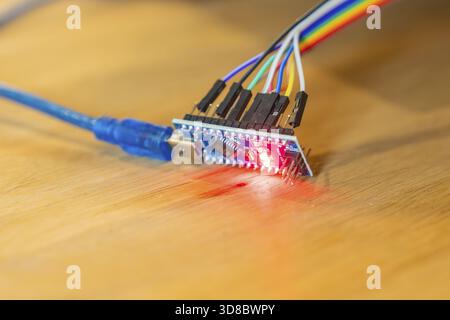 Small circuit board glows red, connected to USB cable, on wooden table, Jugend Forschungszentrum Nagold, Calw district, Germany Stock Photo