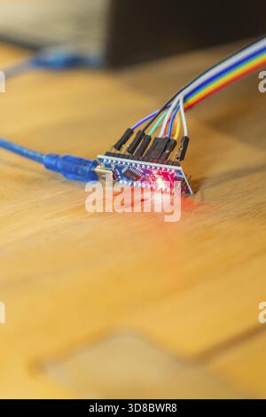 Red glowing circuit board connected to USB cable on wooden table, Jugend Forschungszentrum Nagold, Calw district, Germany Stock Photo