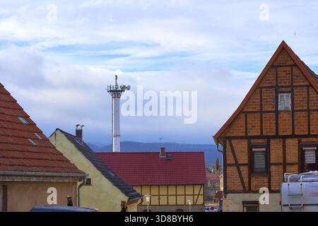 Traditional half-timbered house next to a modern radio tower transmission tower for mobile wireless radio and mobile communications technology in the Stock Photo
