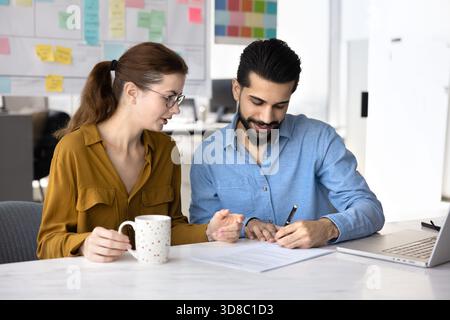 Positive young Middle Eastern businessman signing agreement Stock Photo