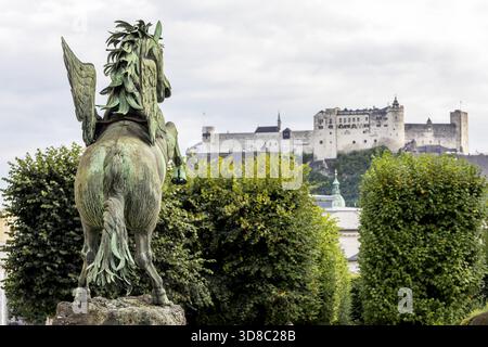 Large horse sculpture on the Pegasus Fountain in the beautiful, well-kept Mirabell Garden at Mirabell Palace and in the background the Nonnberg hill w Stock Photo