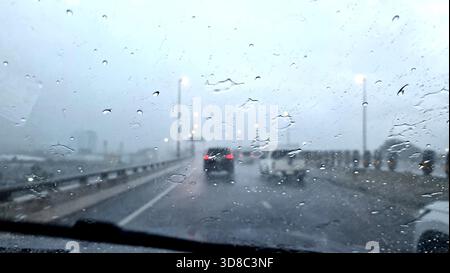 Raindrops on the windshield on a rainy evening on the highway. Stock Photo