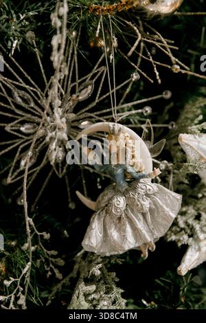 A fairy ornament in a silver dress adorns a festive Christmas tree, surrounded by snowflakes and decorations Stock Photo