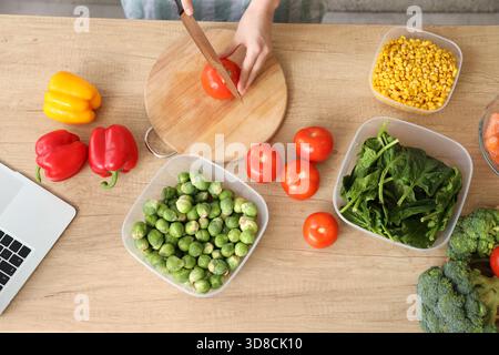 Woman cutting fresh tomatoes for freezing on wooden table Stock Photo