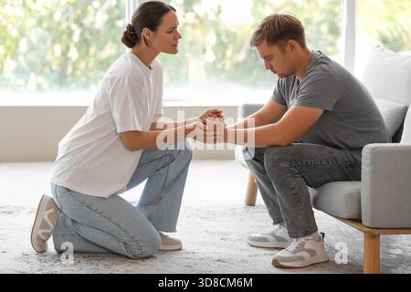 Young woman supporting sad man with suicidal thoughts at home Stock Photo