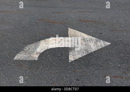 White right arrow sign painted on a grey gray asphalt road surface Stock Photo