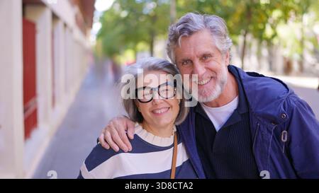 Happy senior couple hugging and smiling outdoors Stock Photo