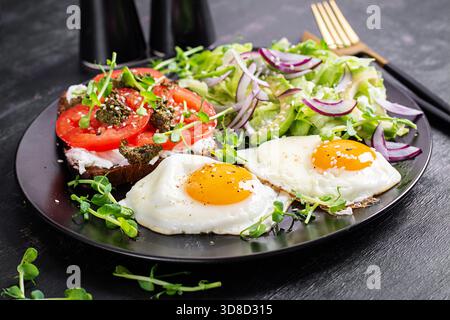 Fried egg, fresh salad and sandwich with tomatoes, pesto and cream cheese. Stock Photo