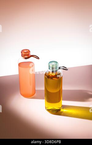 High angle view of colorful reusable water bottles casting long colored shadows on pink aesthetic background Stock Photo