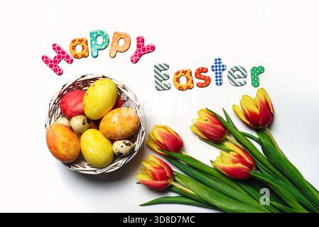 Happy Easter card with painted Easter eggs red and yellow two colored tulip flowers on white background top view flat lay Stock Photo