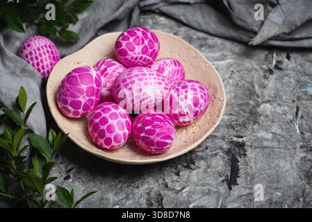 Lace pattern painted pink Easter eggs on a plate on gray background with copy space top view. Easter holiday background Stock Photo