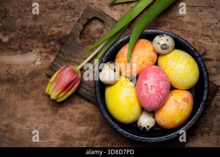 Colorful red and yellow tulips with hand painted Easter eggs on a wooden table tabletop view with copy space Stock Photo