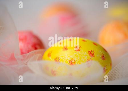 Hand painted pastel colored Easter eggs on white silky fabric closeup Stock Photo