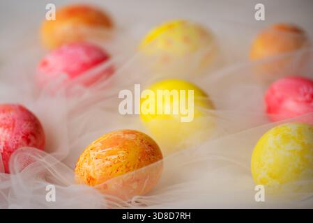 Hand painted pastel colored Easter eggs on white silky fabric closeup Stock Photo