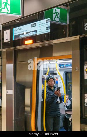 Melbourne, VIC, Australia. November 30, 2025. - A commuter is pictured inside a newly opened Metro Tunnel train at Town Hall Station, viewing digital Stock Photo