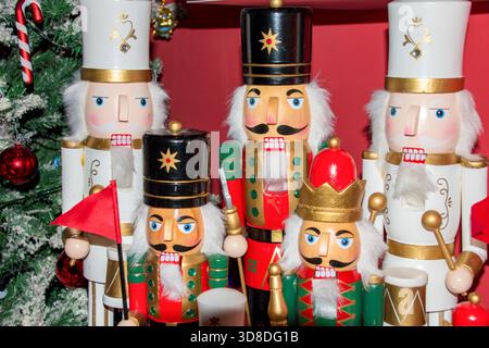 Decorative nutcracker soldiers standing in front of a Christmas tree full of colorful lights and ornaments. Stock Photo