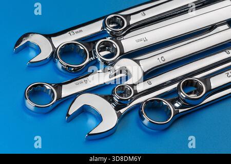 A set of stainless steel open-end and ring spanners of various sizes, laid diagonally on a blue background Stock Photo