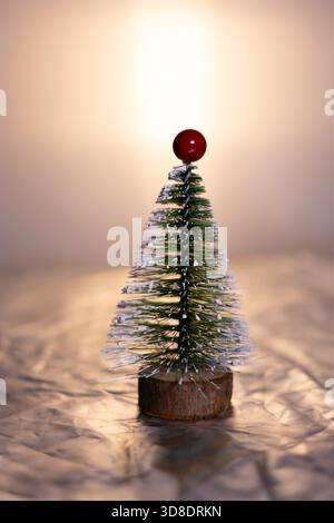 A small decorative Christmas tree with a wooden base, covered in white glitter Stock Photo
