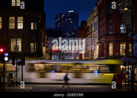 Manchester Metrolink tram on Cross Street with the King Street Christmas Market beyond Stock Photo