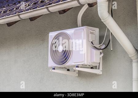 Inverter split system, heating and cooling pump installed under roof of family home Stock Photo