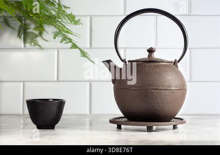 teatime scene with cast iron teapot, cup, on a marble countertop Stock Photo