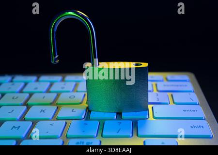 An open padlock sits on a computer keyboard, symbolizing vulnerability in cyber security. The scene has a colorful glow, emphasizing the importance of Stock Photo