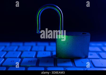 A padlock is positioned upright on a computer keyboard, highlighting the theme of internet security. The dim lighting and blue tones create a sense of Stock Photo