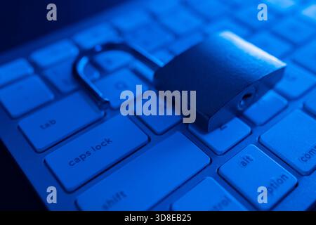 A metal lock lies open on a keyboard, symbolizing cyber security concerns. The dim lighting adds to the atmosphere, emphasizing the importance of inte Stock Photo