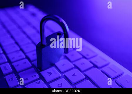 A security lock sits on a computer keyboard, indicating the importance of cyber security in protecting personal information. The scene is illuminated Stock Photo