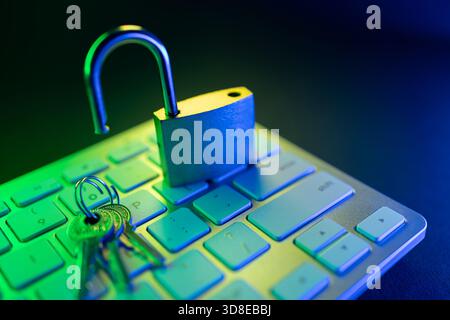 A digital padlock sits open on a computer keyboard, surrounded by keys. The green and blue lighting highlights themes of cyber security and internet s Stock Photo