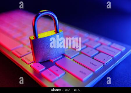 A metallic padlock sits on a computer keyboard, showcasing the vital role of cyber security in protecting online information. This visual highlights t Stock Photo
