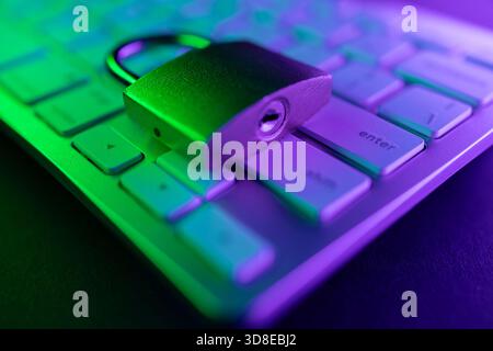 A metal padlock rests on a computer keyboard, symbolizing internet security. The colorful light adds a modern touch to the concept of protecting perso Stock Photo