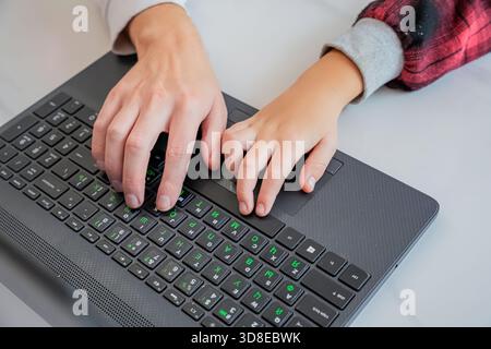 Adult Teaching Child to Type on Laptop Stock Photo