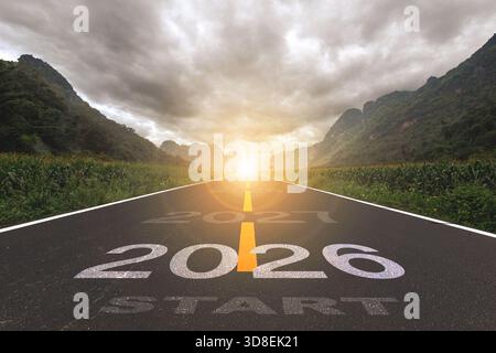 2026, the new year 2026 or the beginning of the concept of the word 2026, written on a road in the middle of a paved road with a sunset mountain backd Stock Photo