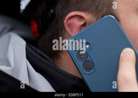 Close-up view of a person using a smartphone for communication during an outdoor conversation in chilly winter surroundings Stock Photo