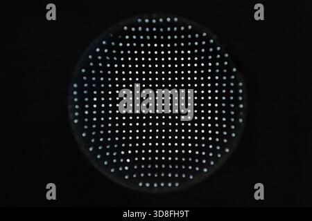 Macro close-up of a circular panel covered in uniform tiny dots against a black background. Conveys precision, technology, and modern sensing; ideal f Stock Photo