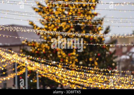 A large outdoor Christmas tree in Vilnius, decorated with warm white lights and ornaments, standing in a festive setting Stock Photo
