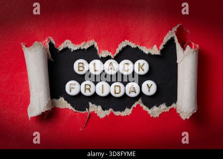 Close-up of Black Friday sale text made of acrylic beads on torn red paper. High-resolution photo. Stock Photo