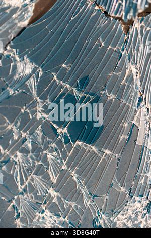 Shattered glass surface with visible Apple logo beneath web-like cracks. Close-up of device damage. Stock Photo