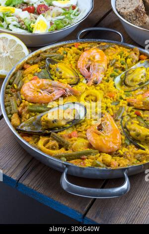 Paella and a bowl of salad on a table Stock Photo