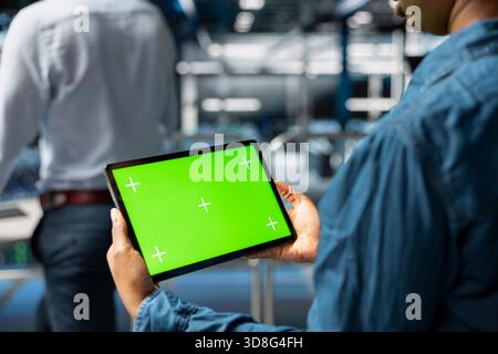 Close up of engineer using green screen mockup tablet in data center to update servers, configuring computer science. Server room admin reviewing hardware analytics on chroma key device. Stock Photo