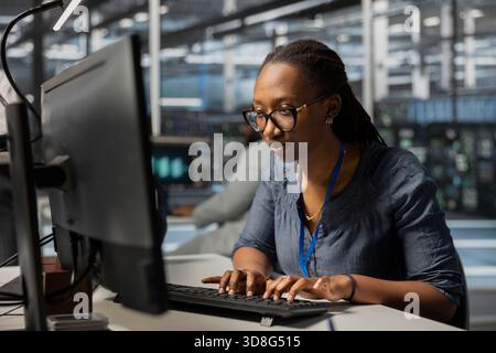 Employee using PC to oversee data center equipment providing processing resources for different workloads. Admin doing maintenance on server rigs tasked with solving complex operations Stock Photo