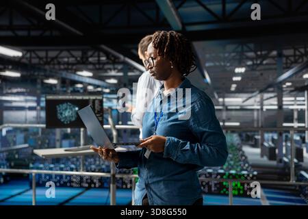 Server farm woman manager overseeing workers doing AI automatization, machine learning for servers infrastructure. Data center supervisor managing configurations with artificial intelligence. Stock Photo