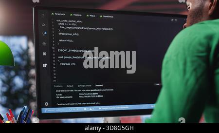 Black system administrator creating a software with programming language. Professional engineer focuses on app development, debugging, encryption and security at home. Camera A. Stock Photo