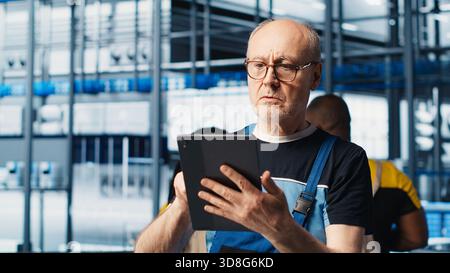 Industrial plant senior engineer implements industry 4.0 automated workflows and control systems, computerizing operations. Elderly specialist integrates sensors into production, camera A closeup Stock Photo