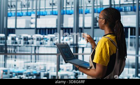 Engineers in industry 4.0 industrial plant controlling automated machinery, ensuring workflow continuity. Technicians in smart factory managing robotic arms and conveyor belts, camera A Stock Photo