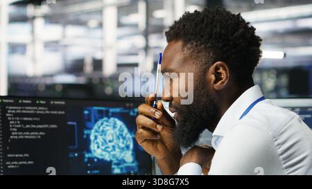 Data center programmer uses neural networks node tree program to identify equipment issues. Server hub employee reviewing AI deep learning data analysis graph to minimize failures, camera B Stock Photo