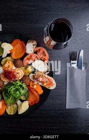 Assorted appetizers and vegetables with bruschetta, falafel and cheese on a dark wooden table. Stock Photo