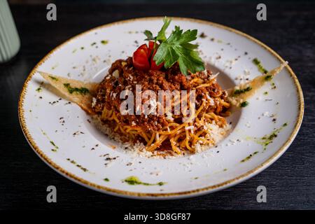 Spaghetti Bolognese with meat sauce, cheese, herbs and toast on a ceramic plate. Rustic table setting. Stock Photo