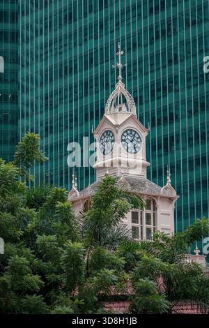 Clock tower on Lau Pa Sat Hawker Center Telok Ayer Market in Singapore with a building in the background Stock Photo